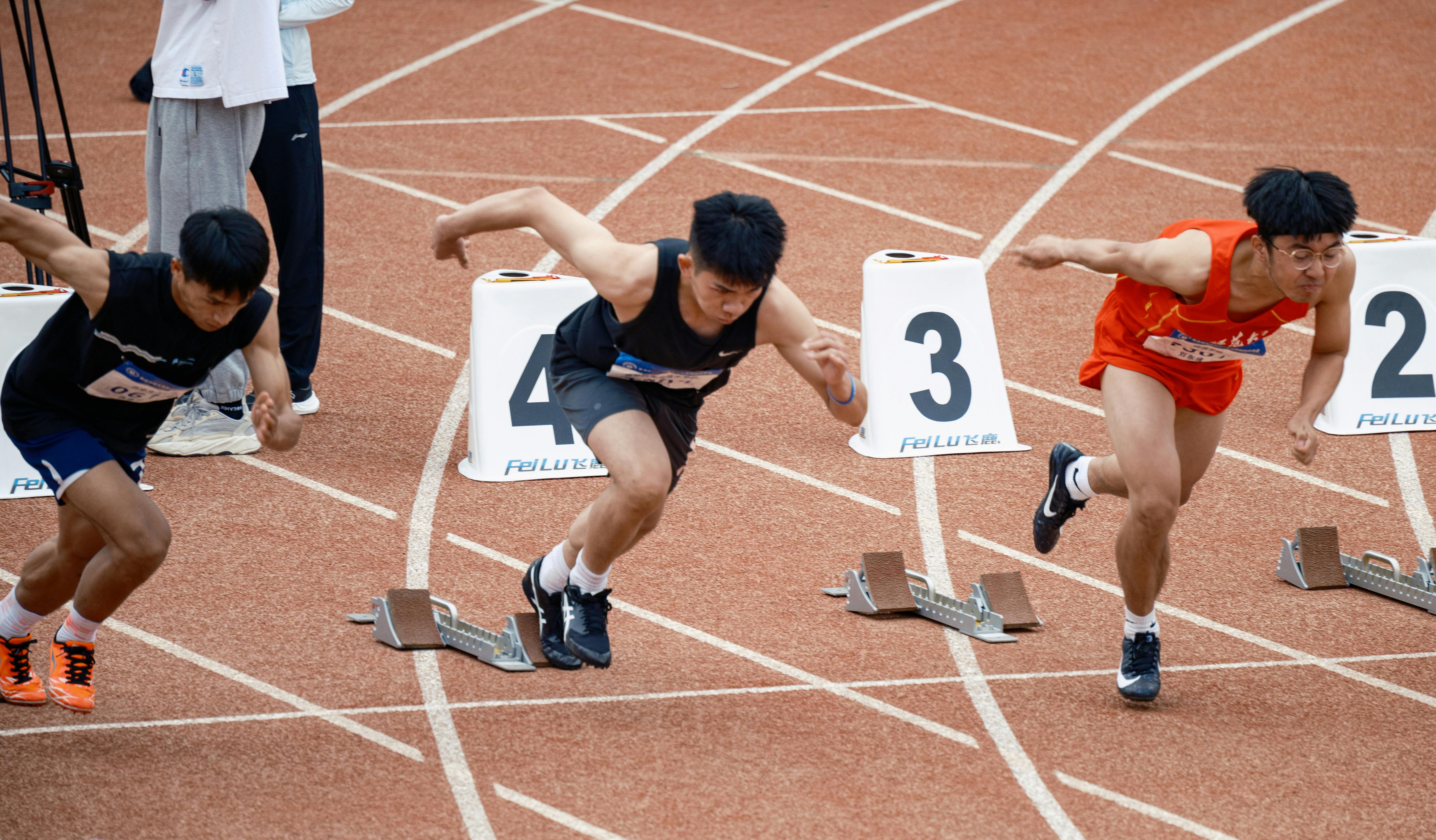 Young male sprinters launching off at the starting line, showcasing athletic determination on the track.